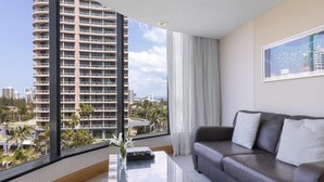 Ein modernes Wohnzimmer mit einem Glastisch, einer Ledersofa und Blick auf ein hohes Gebäude.