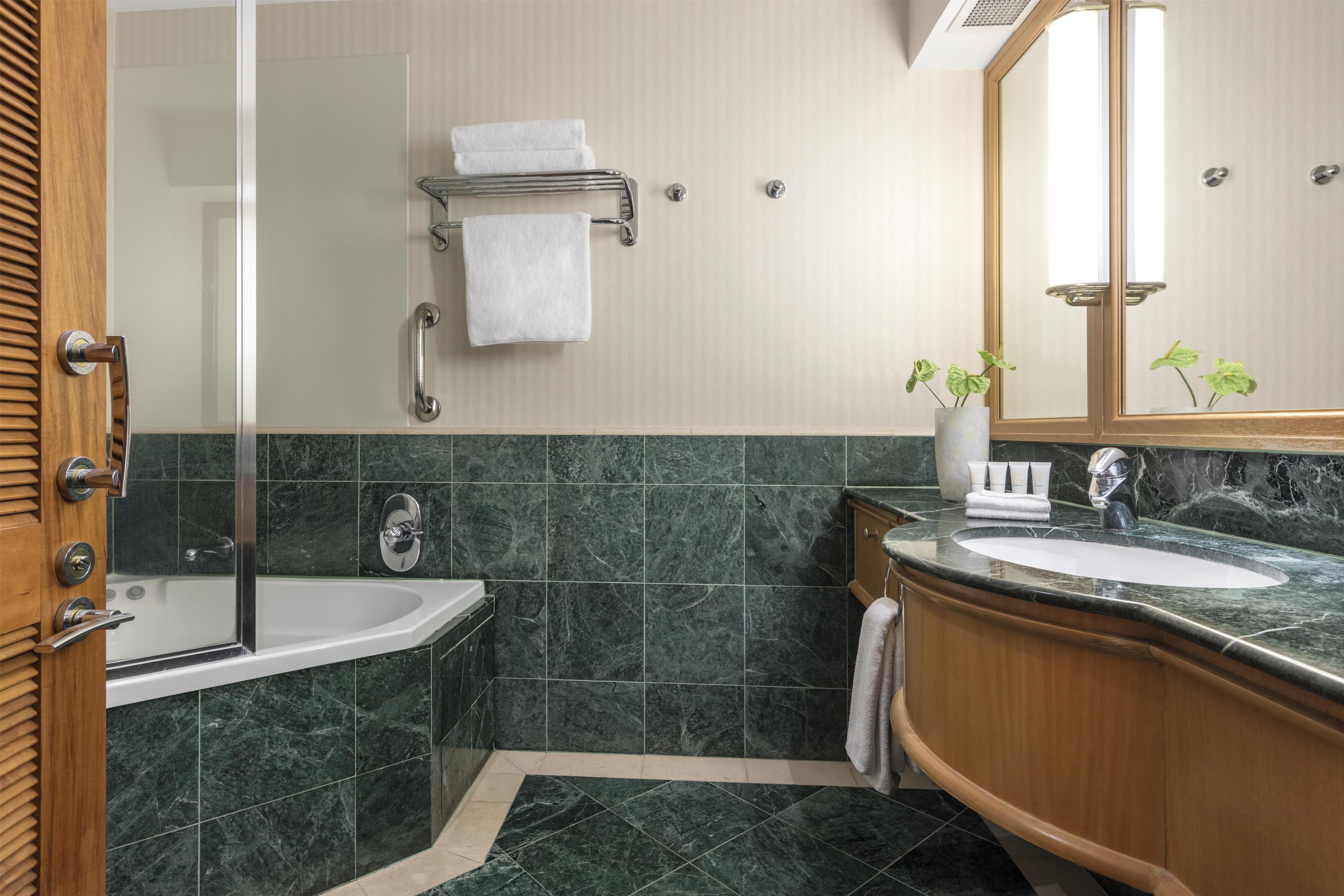 A bathroom with a bathtub, a sink, a mirror, and a towel rack.