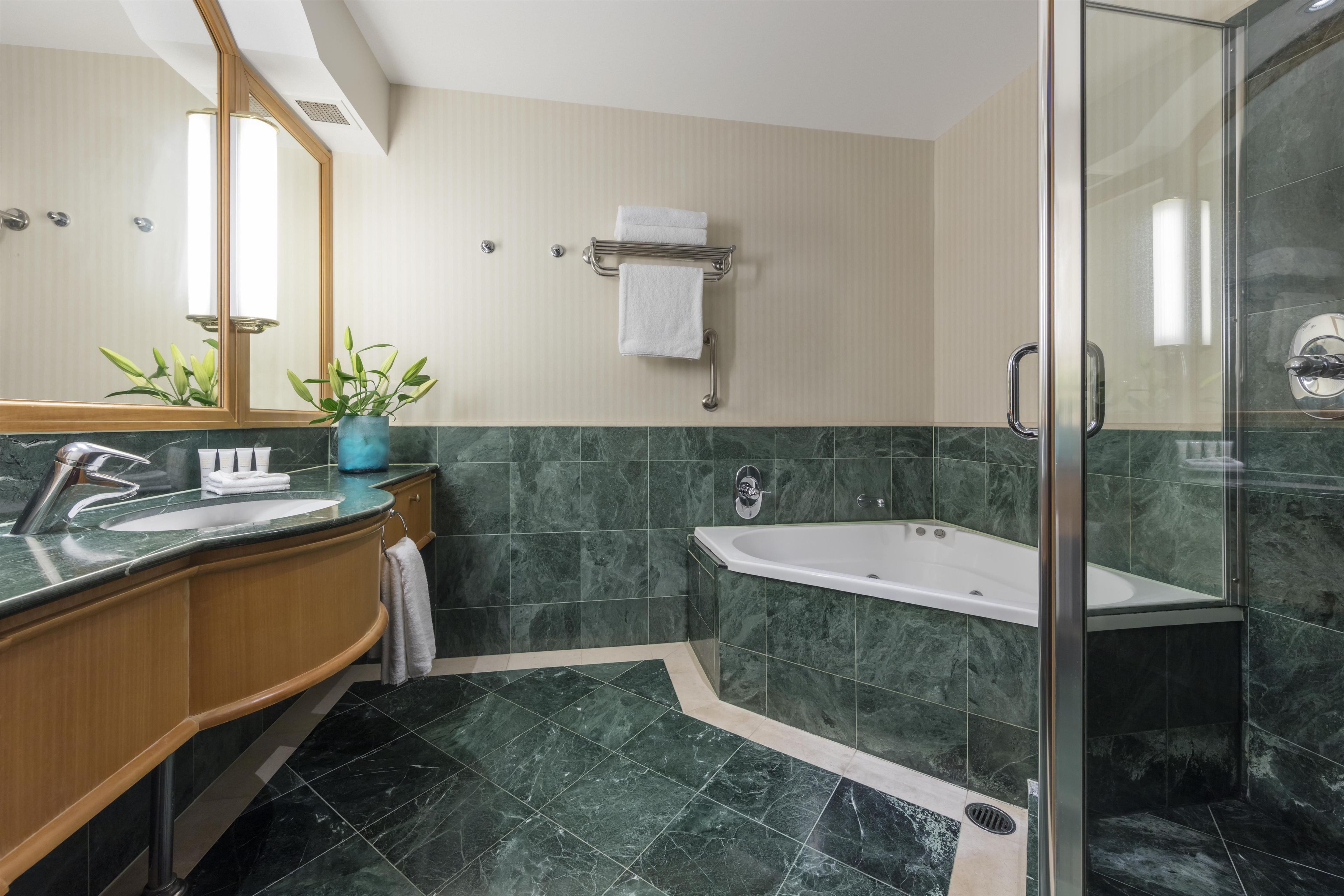 A modern bathroom with a marble floor, a bathtub, a shower, and a vanity with a sink and mirror.