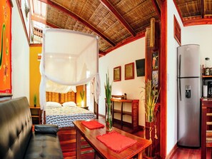 Quarto com cama, mesa de jantar, frigorífico e cozinha.