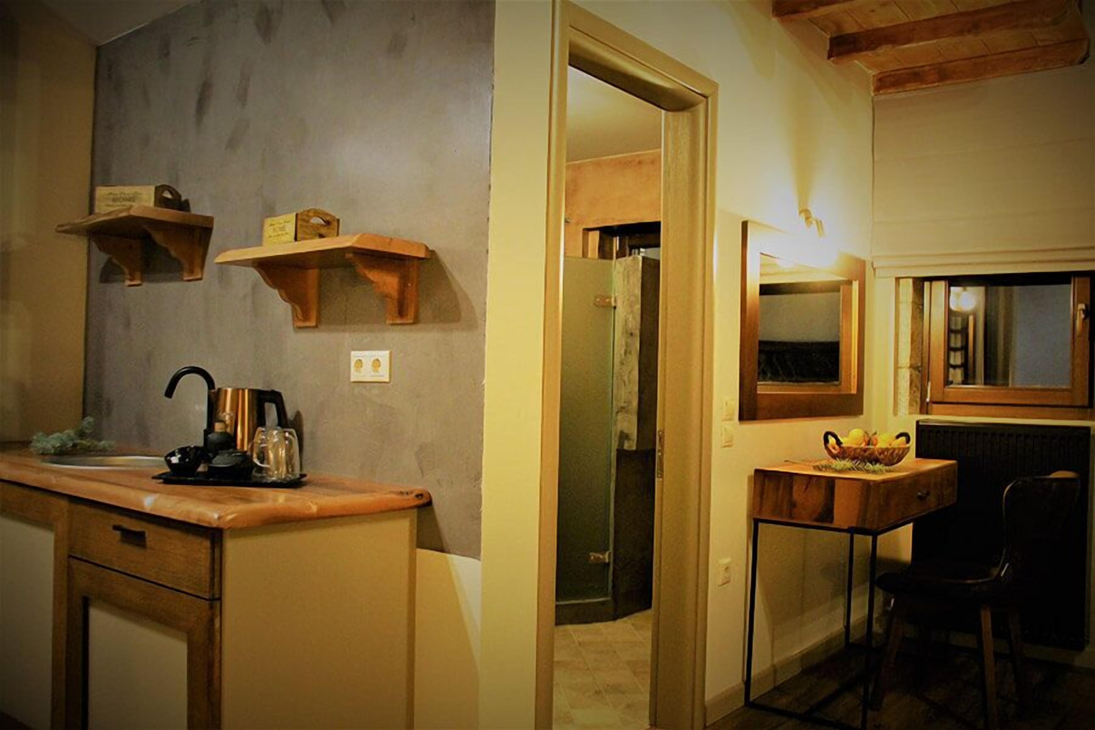 A kitchen with wooden shelves, a coffee maker, and a table with a fruit bowl.
