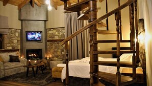 A cozy room with a stone fireplace, a television, a wooden staircase, and a comfortable seating area. - Mylaon Boutique Hotel & Spa (Gortynia)