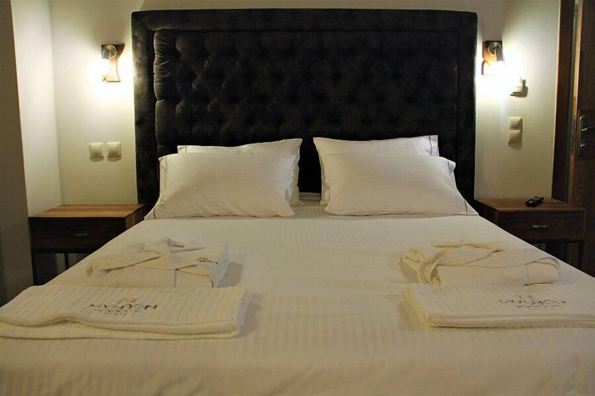 Een hotelkamer met een groot bed, twee nachtkastjes en een donker hoofdeinde.