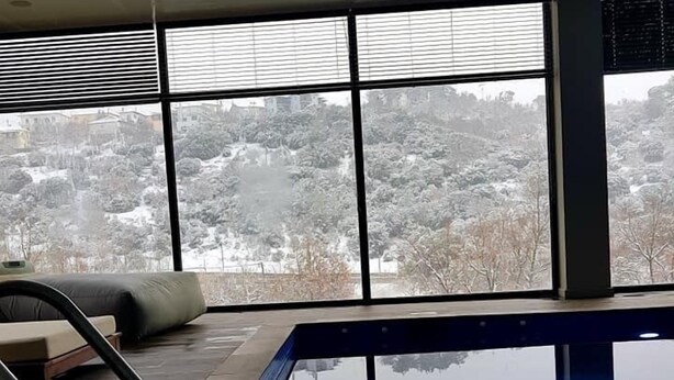 A modern indoor swimming pool with a clear view of a snowy landscape through large windows. - Mylaon Boutique Hotel & Spa (Gortynia)