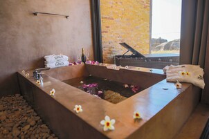 Un baño tipo spa con una bañera grande, un piano y vistas a un paisaje rocoso.