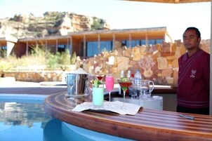 A poolside bar with various drinks and a bartender.