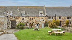 A stone building with a grassy courtyard and a picnic table. - Host & Stay | The Coach House (Whitby)