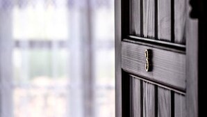 A wooden door with a brass handle, partially obscured by a shadow. - Hotel Gorica (Berat)
