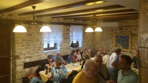 A restaurant with stone walls, wooden beams, and pendant lighting. Tables are set for dining. - Hotel Gorica (Berat)