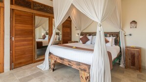 Un dormitorio con cama con dosel, suelo de madera y un espejo grande.