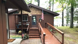 A wooden building with a stone facade, a front porch, and a staircase leading to a door.