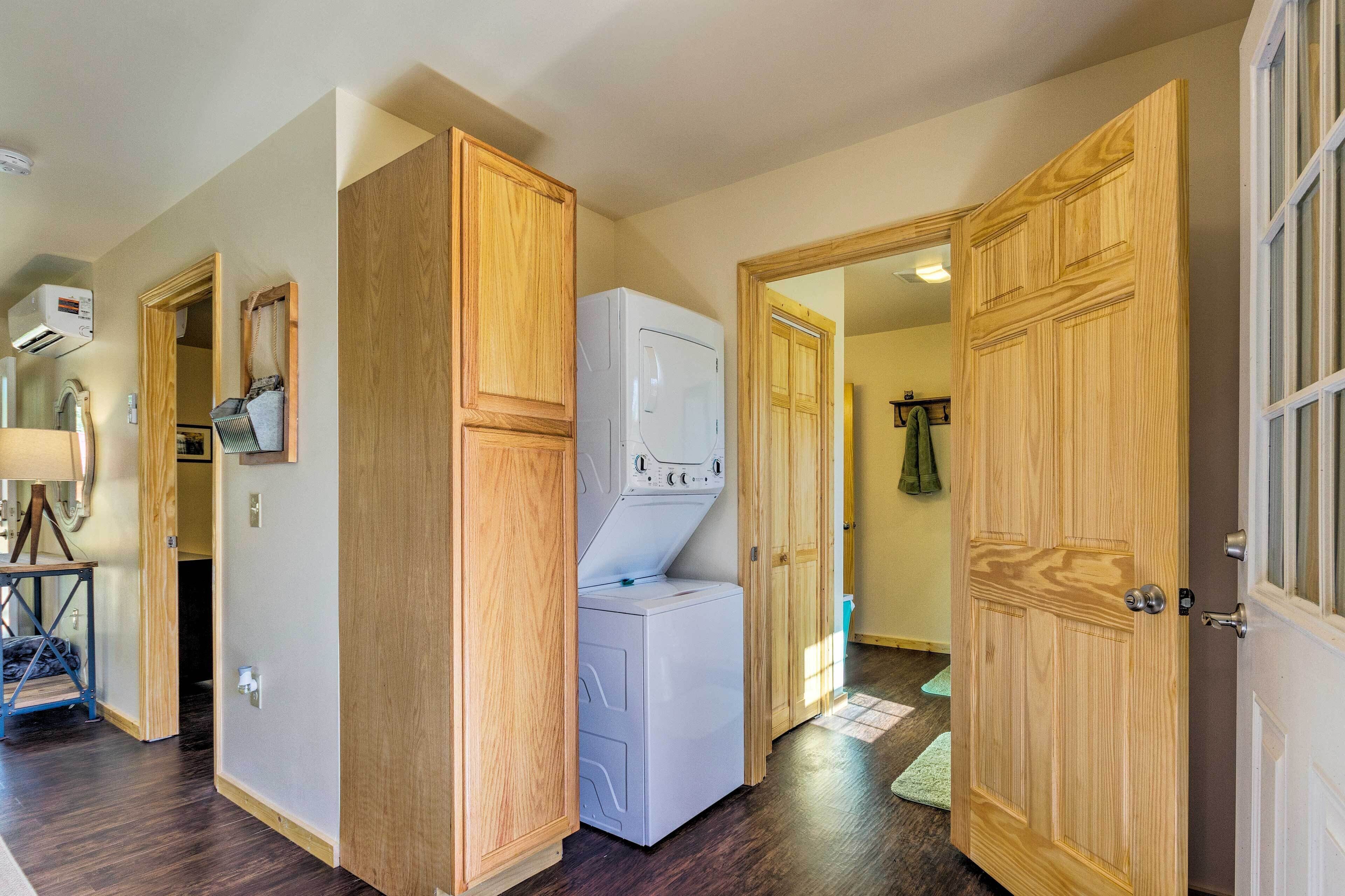A laundry room with a washer and dryer, wooden cabinets, and a door leading to another room.