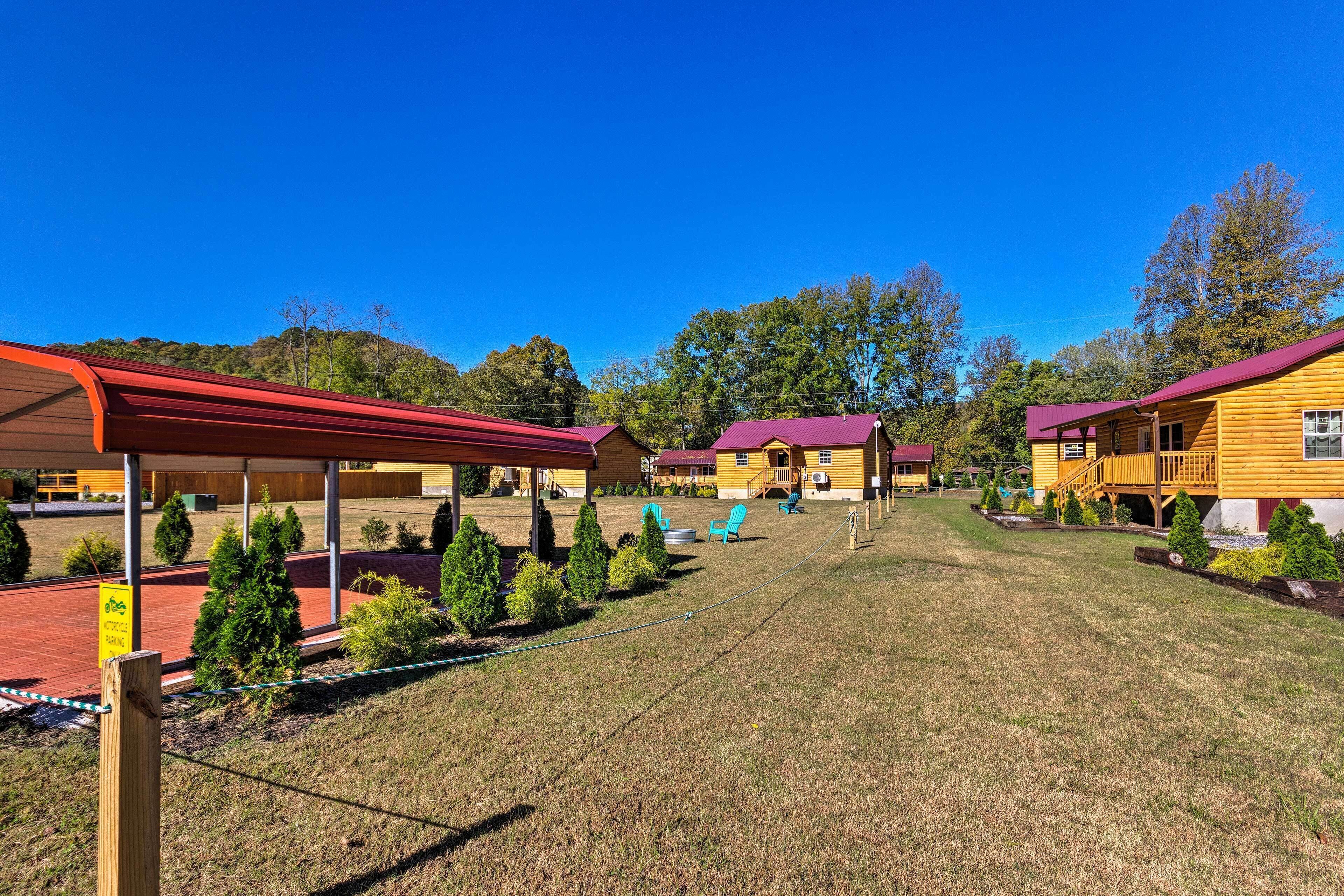 A row of yellow cabins with red roofs, a covered picnic area, and a grassy field.