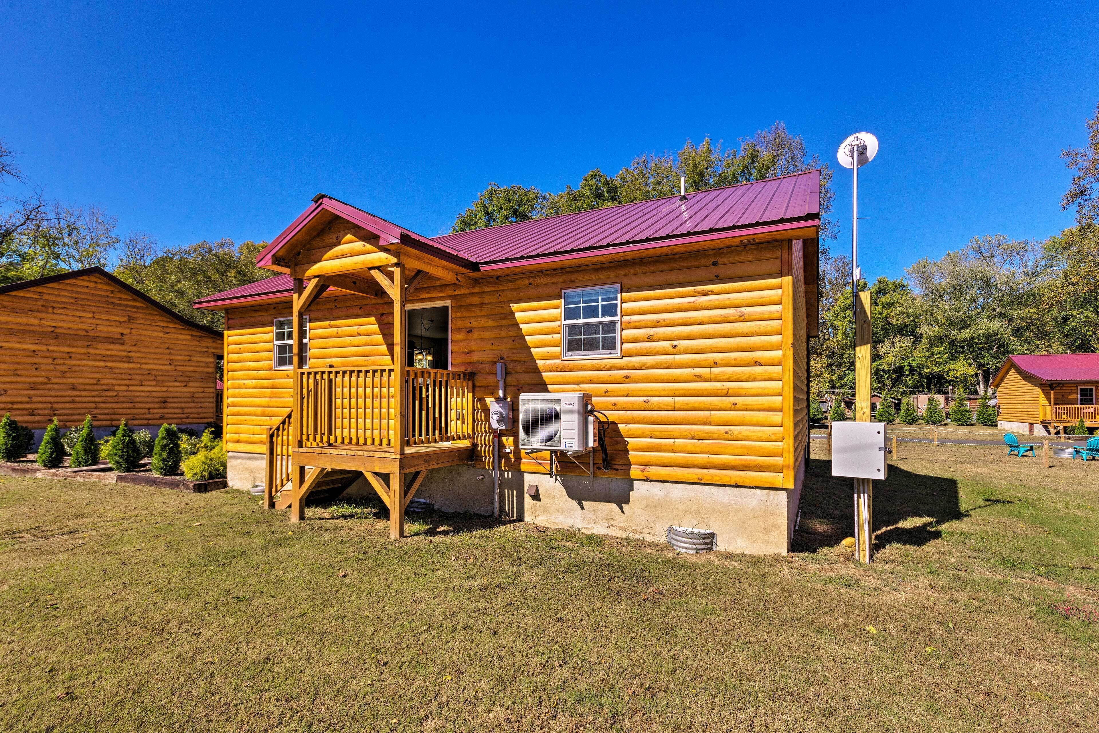 A log cabin with a porch, a satellite dish, and an air conditioning unit.