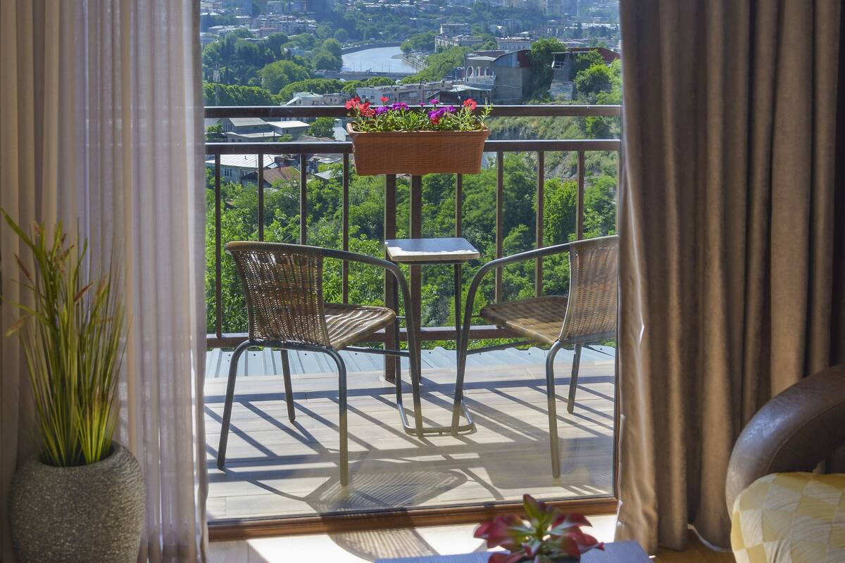 A balcony with two chairs, a table, and a potted plant.