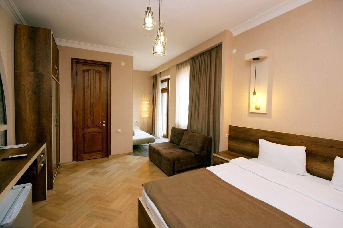 A hotel room with a bed, a sofa, a desk, and a wardrobe.