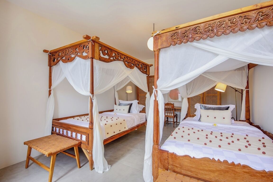 Una cama tradicional con dosel y dosel a juego, un banco de madera, en una habitación de hotel.