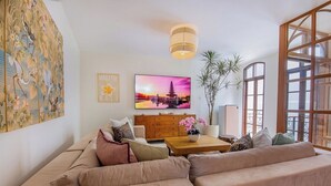 Una sala de estar moderna con un sofá beige, una mesa de centro de madera y un cuadro grande de un atardecer.