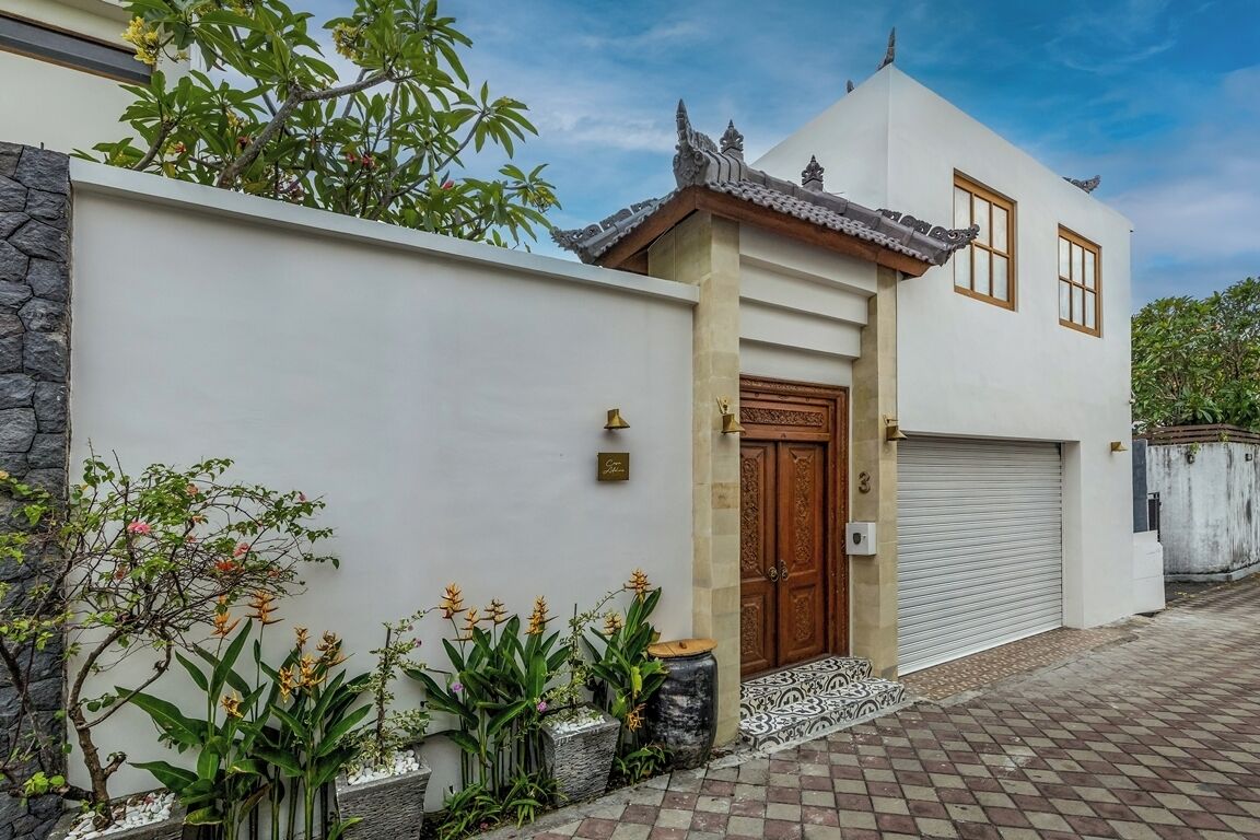 A modern house with a traditional entrance, a garage, and a well-maintained garden with tropical plants.
