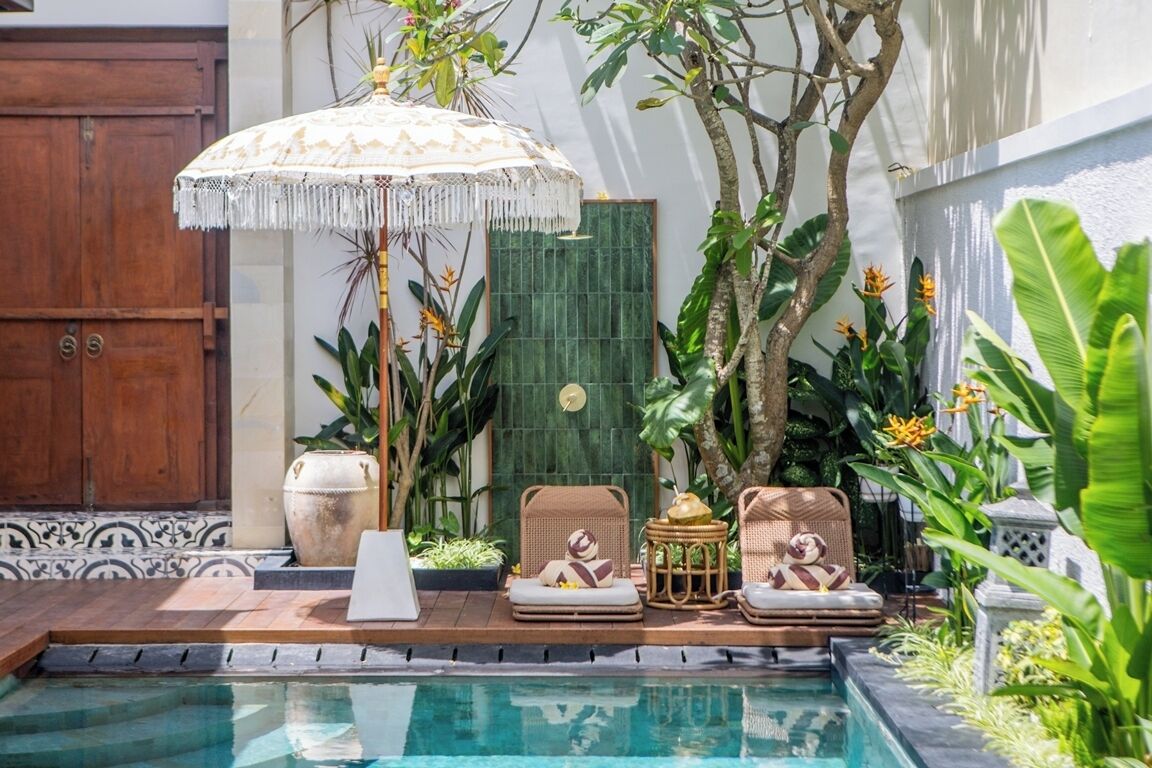 A poolside area with a lounge chair, a small table, and a decorative umbrella.