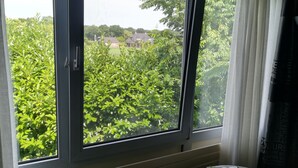 A room with a large window overlooking a garden. - B&B Bovenweg (Rhenen)