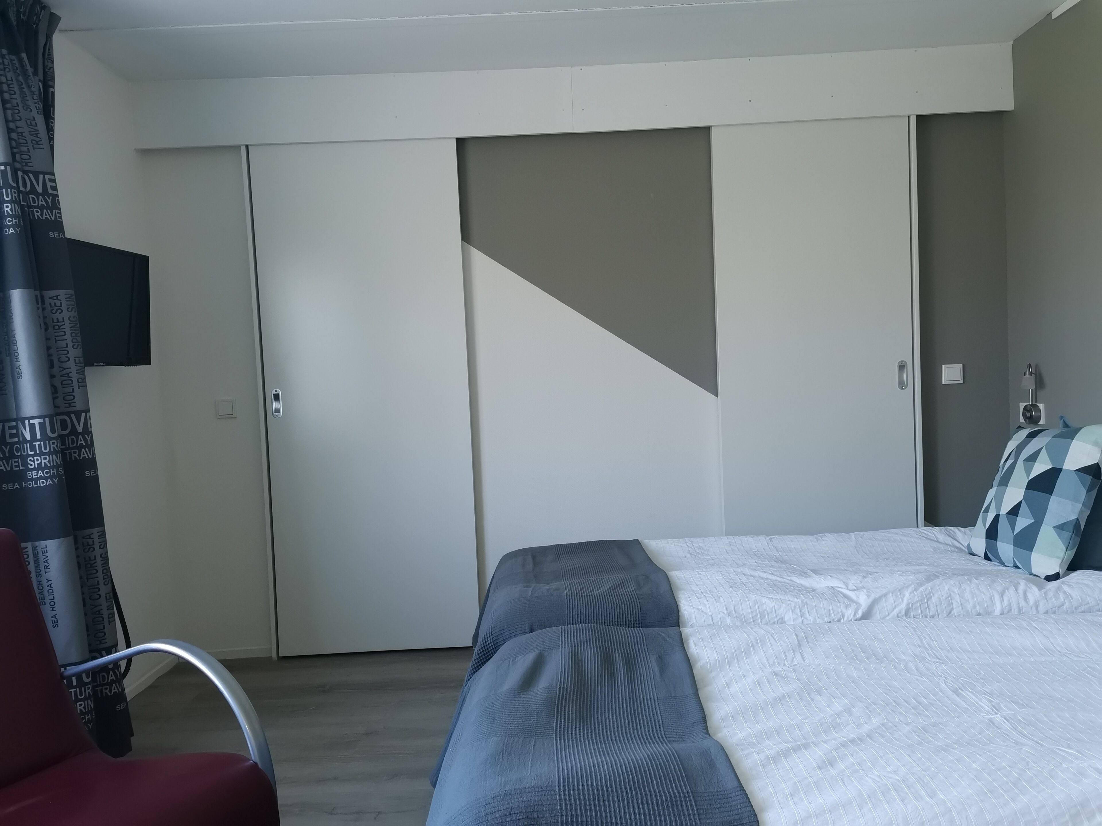 A bedroom with a bed, a wardrobe, and a chair.