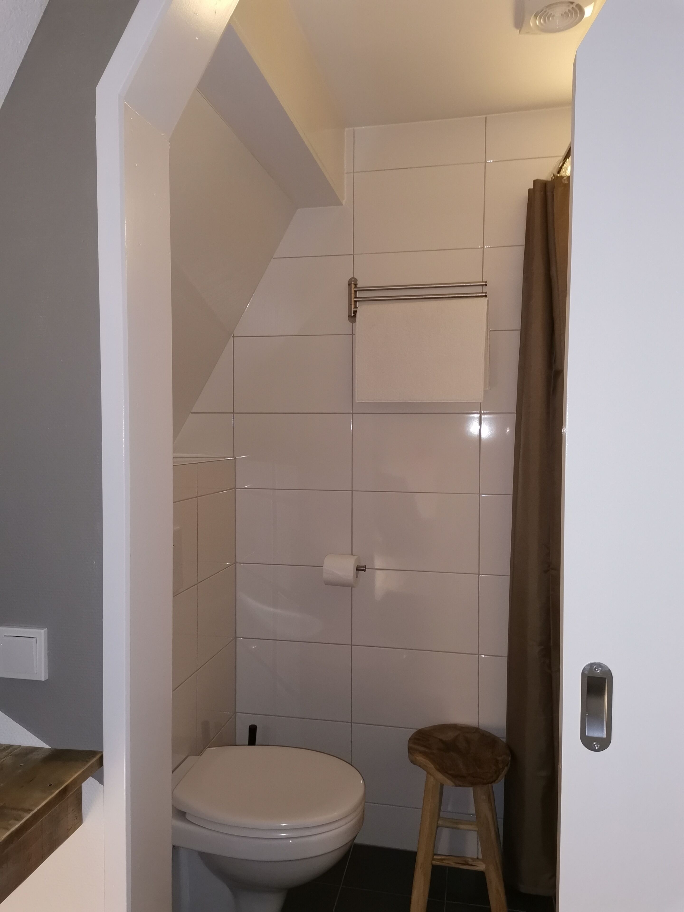 Ein kleines, kompaktes Badezimmer mit Toilette, Handtuchhalter und Duschvorhang.