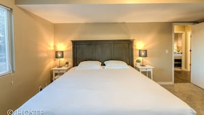 A neatly made bed with two bedside tables, each with a lamp, in a room with beige walls and a wooden headboard. - 2BR Garden of the Gods Hike, Dine, Nightlife! (Colorado Springs)