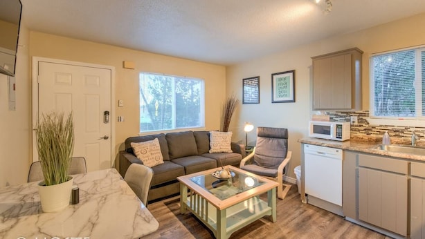 A cozy living room with a sofa, armchair, and coffee table, a kitchen with a microwave, and a dining area with a marble table. - 2BR Garden of the Gods Hike, Dine, Nightlife! (Colorado Springs)
