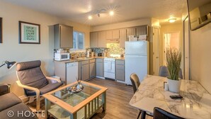 A compact living space with a kitchenette, a dining area, and a seating area with a glass-top coffee table. - 2BR Garden of the Gods Hike, Dine, Nightlife! (Colorado Springs)