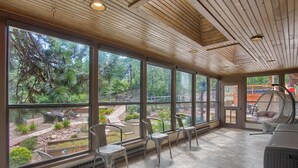 Amplia habitación con grandes ventanales que ofrecen vistas a un jardín y zona de estar exterior.