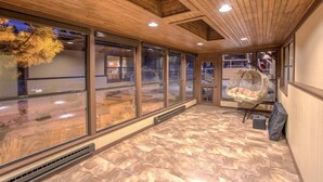 Una habitación amplia con ventanas grandes, un sillón colgante y techo de madera.