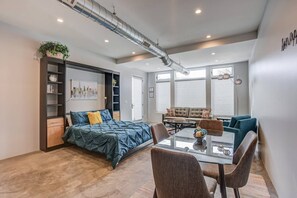 A modern bedroom with a bed, a desk, and a sofa. There is a window and a plant. - 1BD Studio Downtown Close to Hiking W/ac! (Colorado Springs)