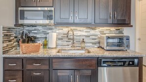 Una cocina moderna con armarios de madera oscura, un microondas de acero inoxidable, un tostador y un lavavajillas.