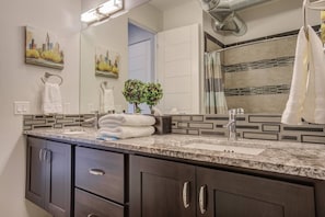 Un baño moderno con un espejo grande, dos lavamanos, armarios de madera oscura y toallas decorativas.