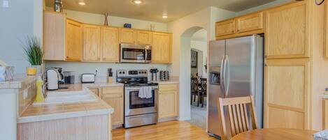 A modern kitchen with wooden cabinets, stainless steel appliances, and a wooden dining table.