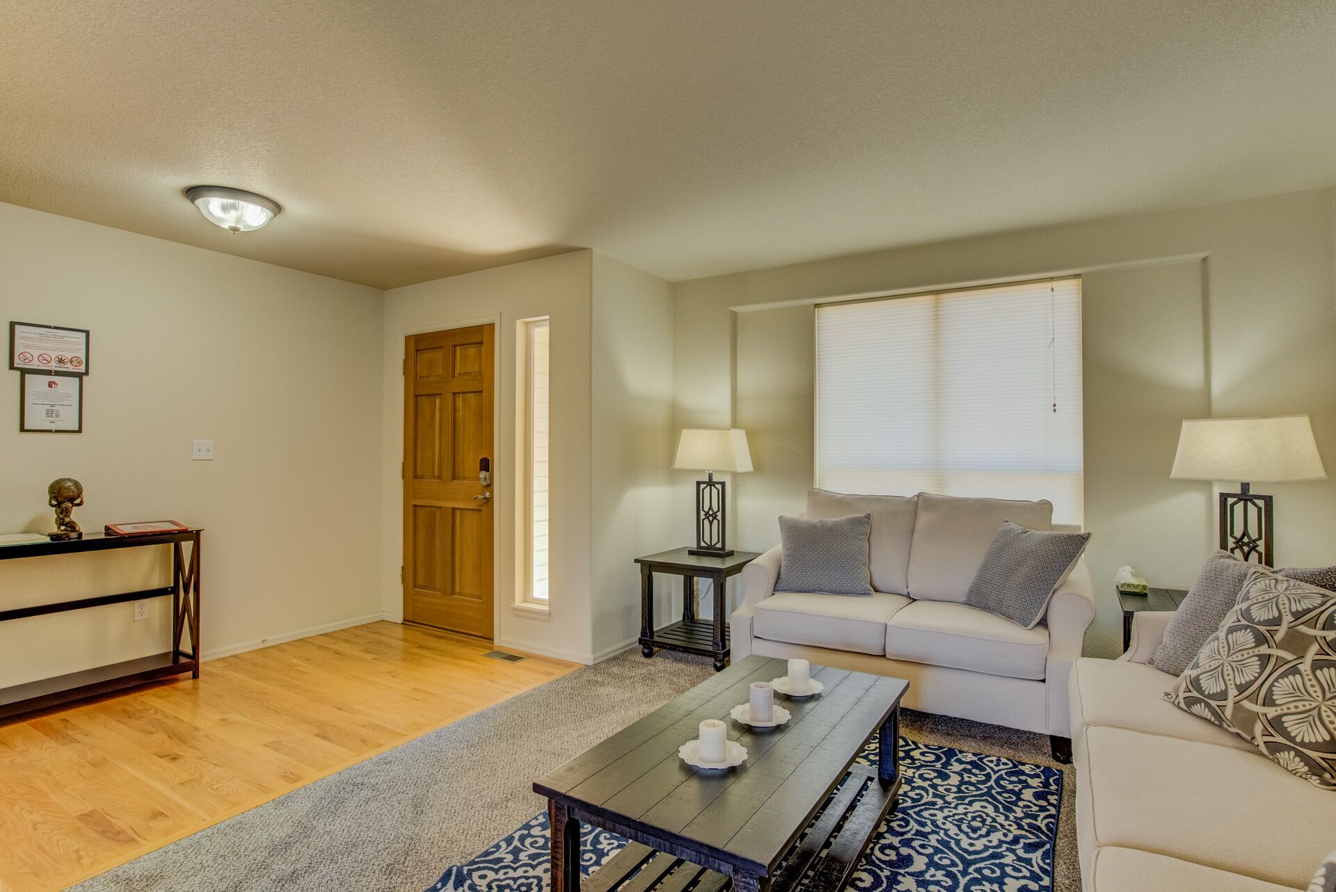 A living room with a wooden coffee table, two lamps, a sofa, and a patterned rug.