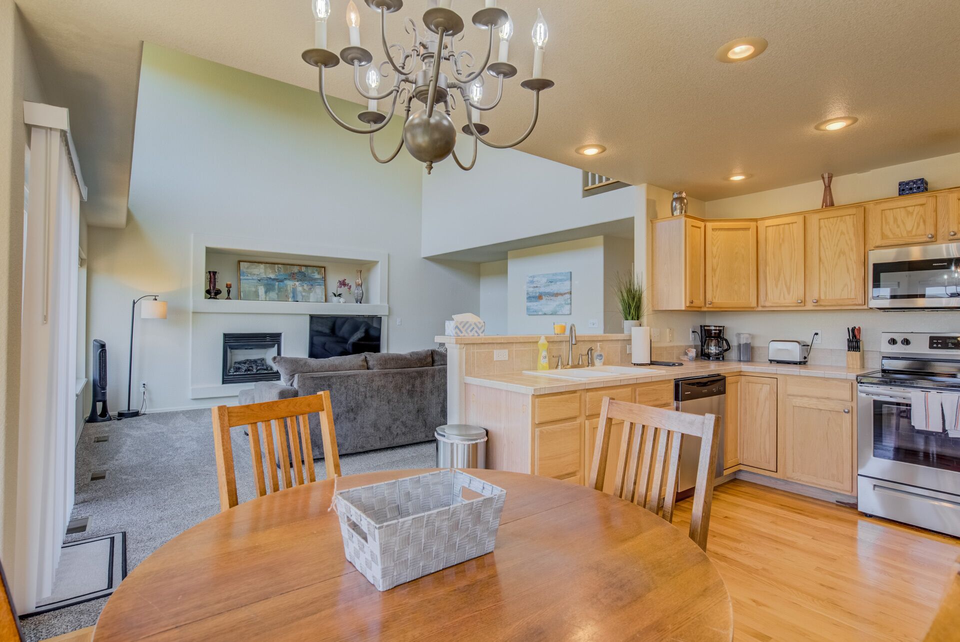 A modern kitchen with wooden cabinets, a built-in oven, and a dining area with a round table and chairs.