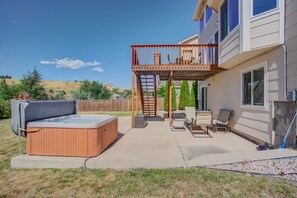 A backyard with a hot tub, patio furniture, and a wooden deck. - 5BR Theatre & Arcade AF Academy Trails, W/hot Tub! (Colorado Springs)