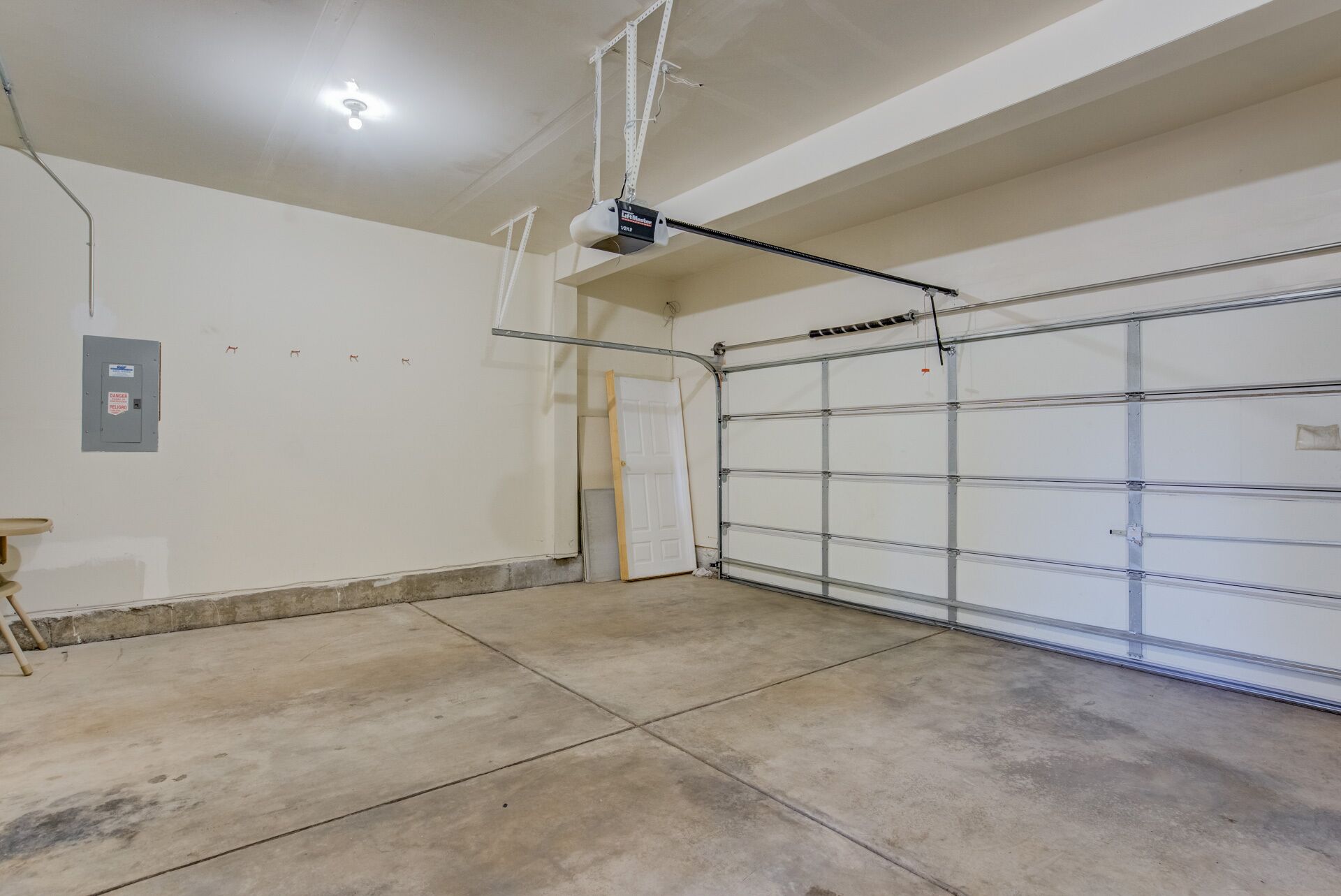 A clean, empty garage with a concrete floor, a metal garage door, and a ceiling light fixture.
