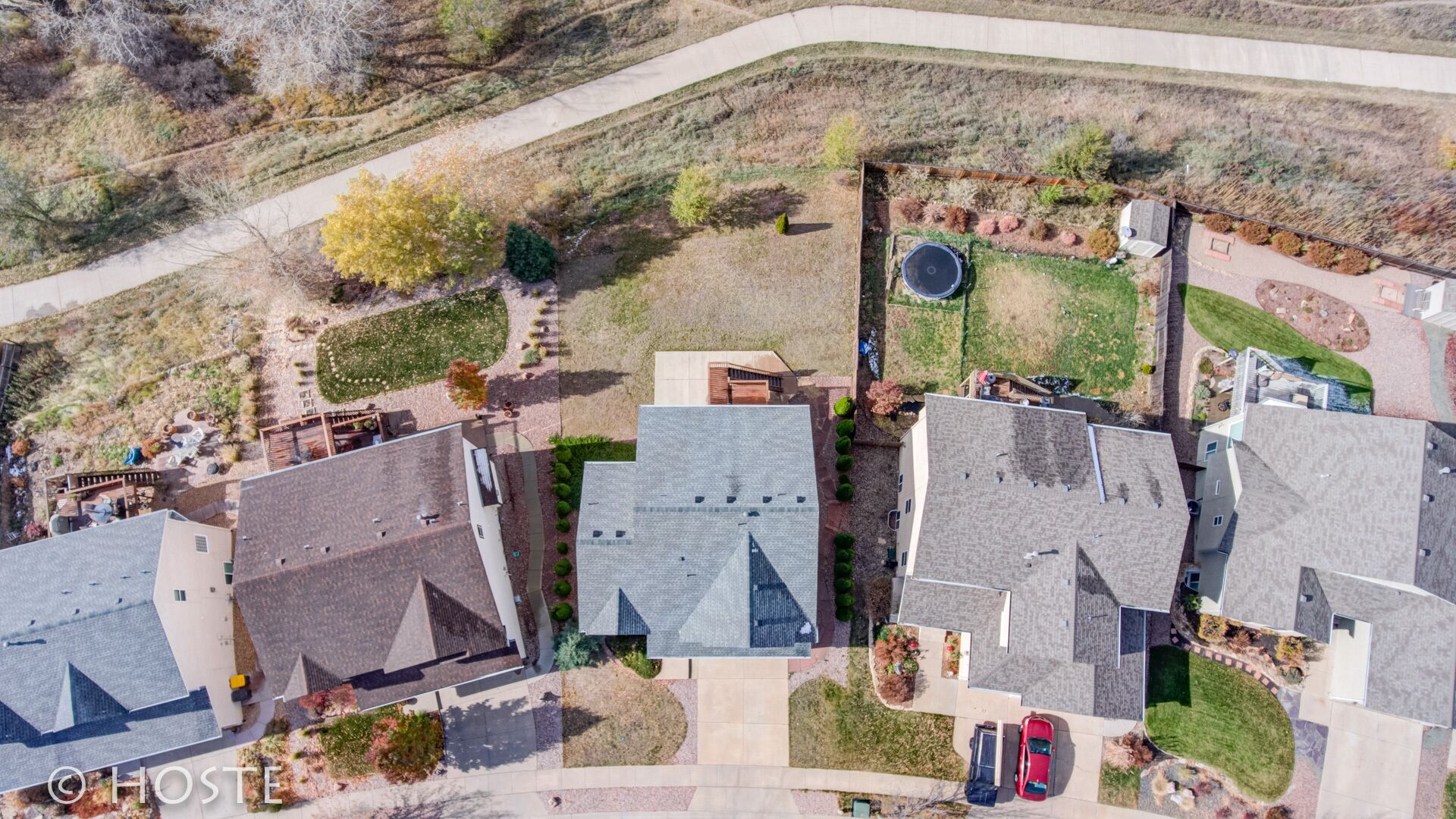 An aerial view of a residential area with multiple houses, a central walkway, and a small park area.
