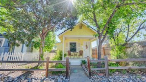 A yellow house with a porch, surrounded by trees and a white picket fence. - Craft Brewery Perfection! Charming & Dog-friendly (Colorado Springs)