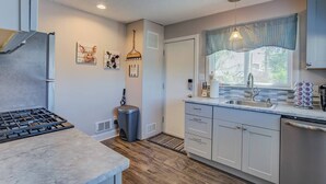 A modern kitchen with a gas stove, a sink, and a window with blinds. - Craft Brewery Perfection! Charming & Dog-friendly (Colorado Springs)