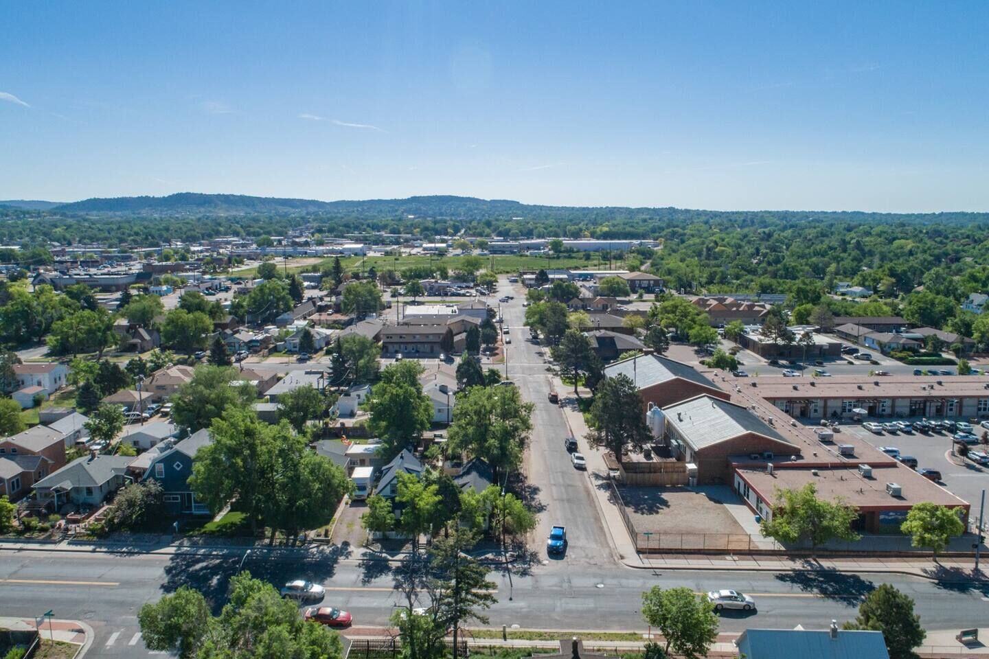 An aerial view of a town with residential houses, a main road, and a large industrial building.