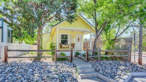 A yellow house with a porch, surrounded by a wooden fence and a gravel pathway leading to the entrance. - Craft Brewery Perfection! Charming & Dog-friendly (Colorado Springs)