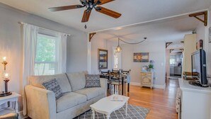A living room with a sofa, coffee table, and a dining area with chairs and a chandelier. - Craft Brewery Perfection! Charming & Dog-friendly (Colorado Springs)