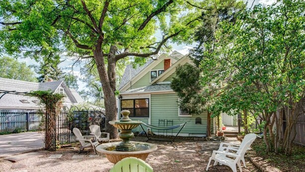 Uma casa com jardim, mobiliário de exterior e uma fonte.