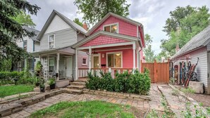 A two-story house with a front porch, a small garden, and a wooden fence.