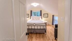 A bedroom with a bed, bedside tables, a window with curtains, and a door.