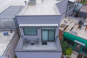 A modern building with a flat roof, large windows, and a small outdoor seating area with two chairs and a table. - 3BR Modern Marveldowntown Customprivate Balcony (Colorado Springs)
